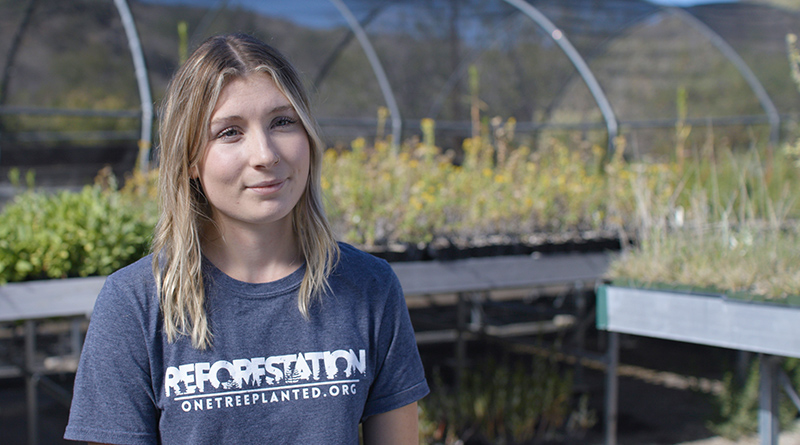 Woman sitting in front of a greenhouse