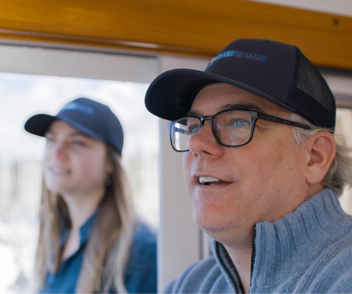 A man and young woman look out at sea from the cabin of a boat.